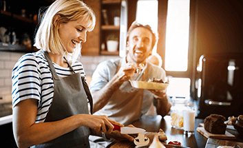 Woman and man smiling together while baking in a kitchen