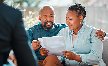 Couple smiling while reviewing paperwork together with an advisor