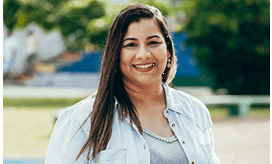 Smiling woman standing outdoors in a denim jacket
