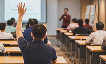 Man raising his hand to ask a question during a classroom seminar