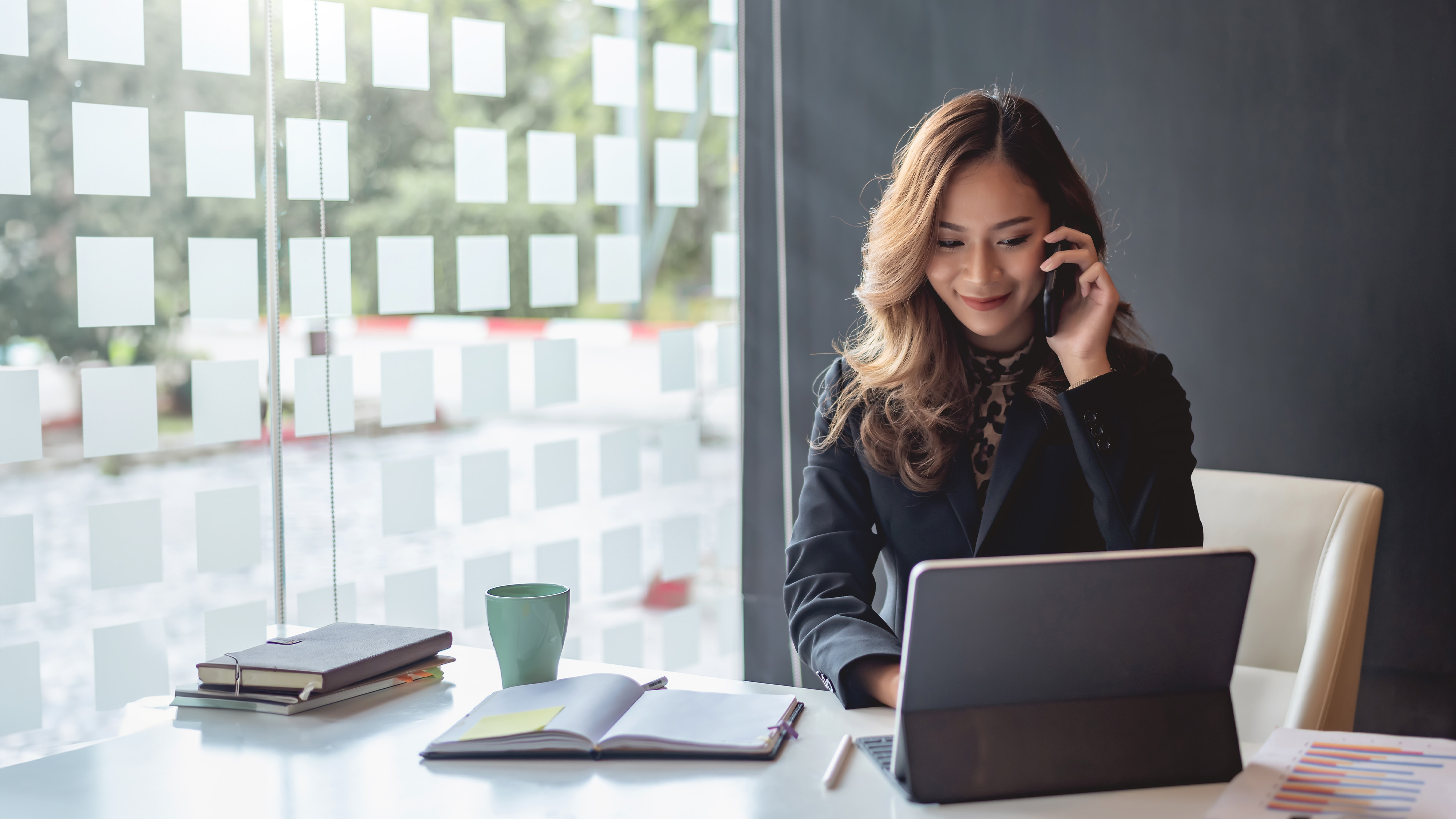A businesswoman smiling while talking on the phone at her desk