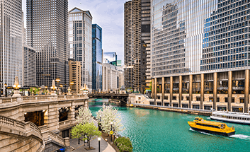 Chicago skyline and river with a water taxi passing beneath a bridge