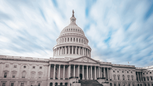 The U.S. Capitol building beneath a dramatic sky with streaking clouds.