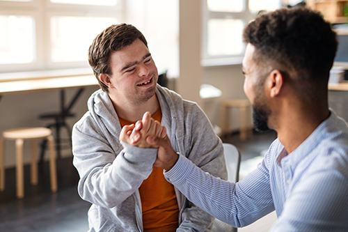 Two men smiling and clasping hands together in an office setting